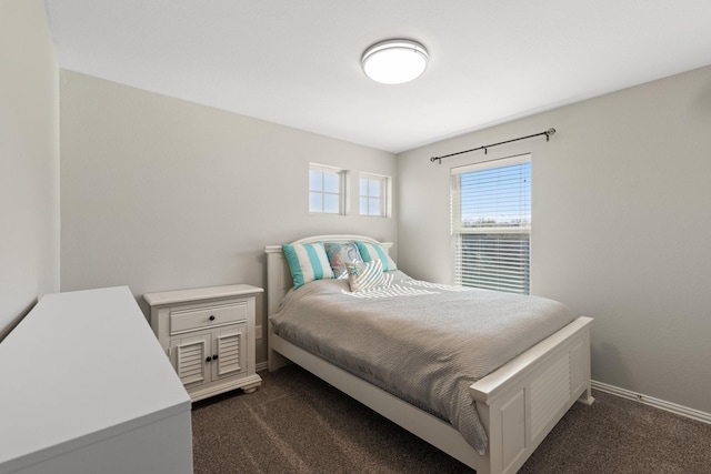 bedroom with dark colored carpet and baseboards