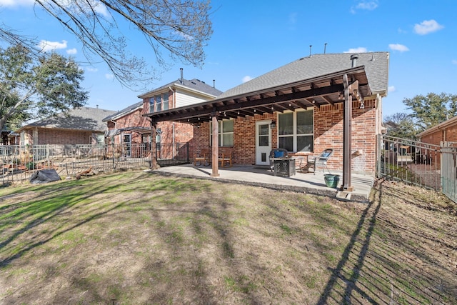 rear view of house with brick siding, a patio, a shingled roof, a lawn, and fence