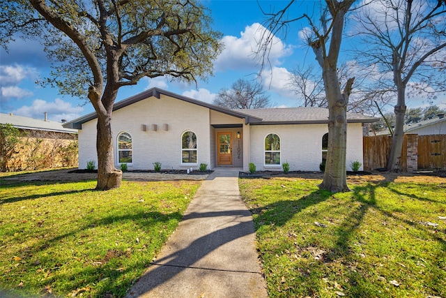 mid-century home featuring fence, a front lawn, and brick siding