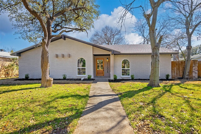 mid-century inspired home featuring brick siding, a front lawn, and fence