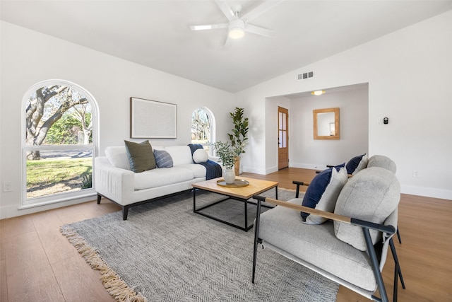 living room with visible vents, ceiling fan, vaulted ceiling, wood finished floors, and baseboards