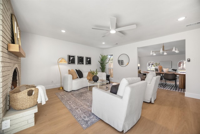 living room featuring recessed lighting, visible vents, a fireplace, and light wood-style flooring