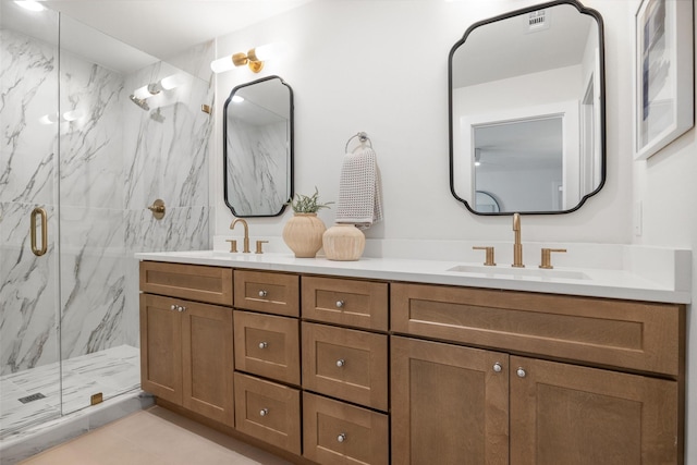 full bath with a marble finish shower, double vanity, a sink, and visible vents