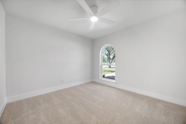 carpeted empty room with a ceiling fan and baseboards