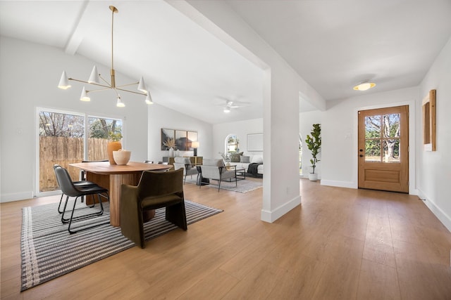 dining area with baseboards, ceiling fan with notable chandelier, vaulted ceiling with beams, and light wood finished floors