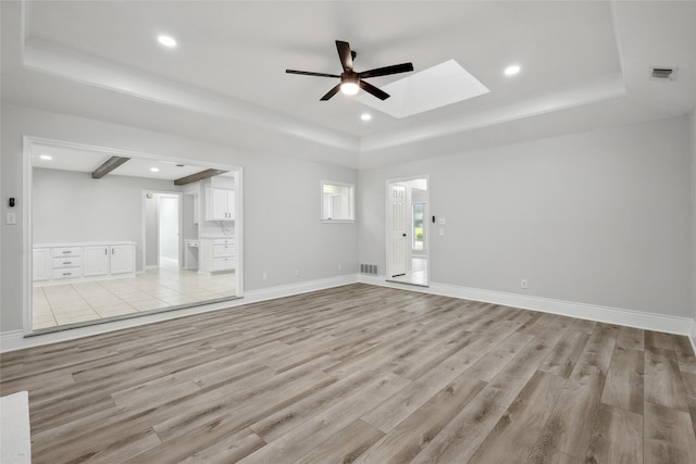 unfurnished living room featuring baseboards, a tray ceiling, light wood-type flooring, and recessed lighting