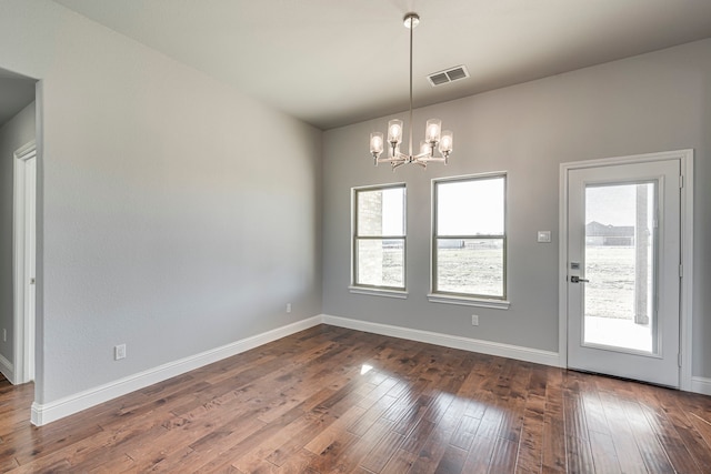 unfurnished room featuring dark wood-style floors, visible vents, baseboards, and an inviting chandelier