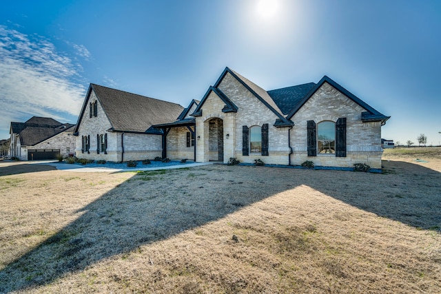 french country style house with a front yard and brick siding