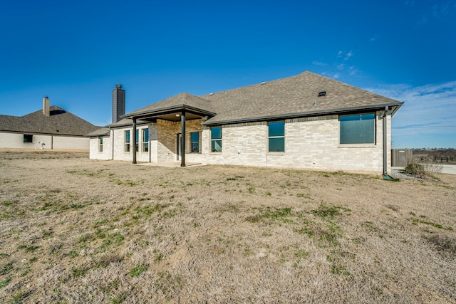 back of house with brick siding and a shingled roof