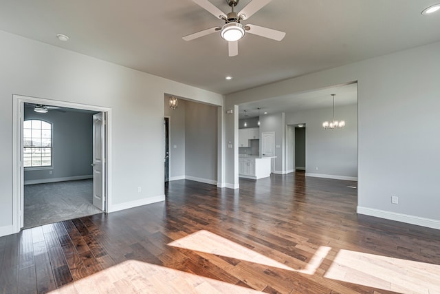 unfurnished living room with recessed lighting, baseboards, dark wood-type flooring, and ceiling fan with notable chandelier