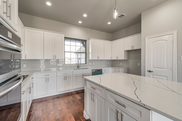 kitchen with light stone counters, white cabinets, dishwasher, and oven