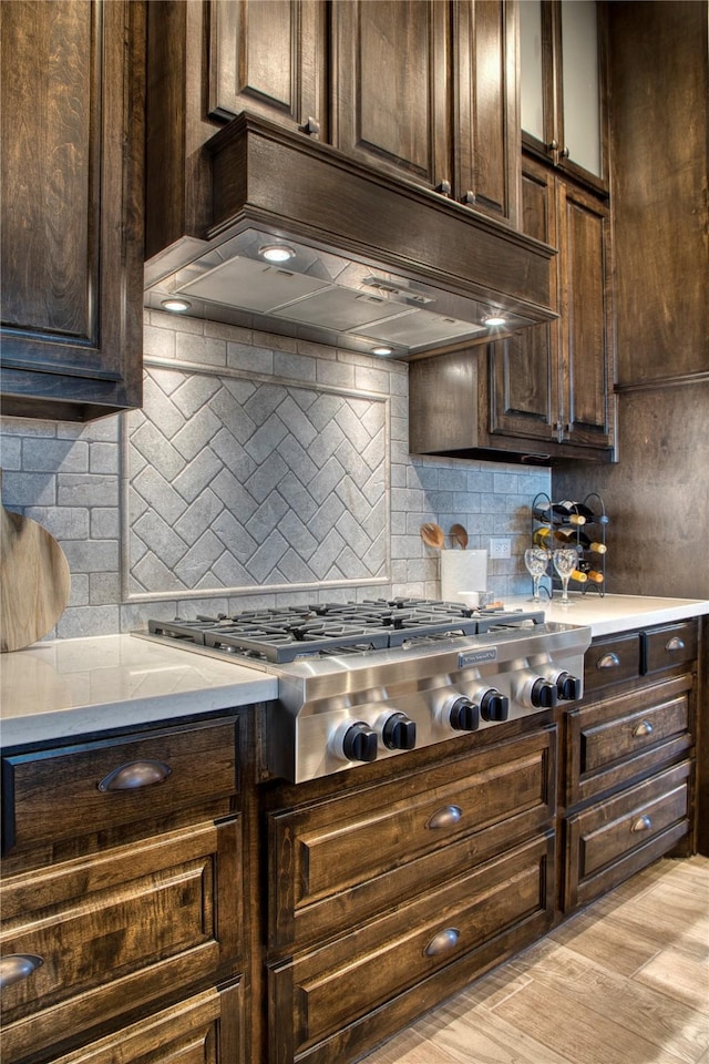 kitchen featuring stainless steel gas stovetop, custom exhaust hood, and dark brown cabinets