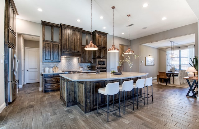 kitchen featuring stainless steel appliances, a spacious island, dark wood finished floors, and decorative backsplash