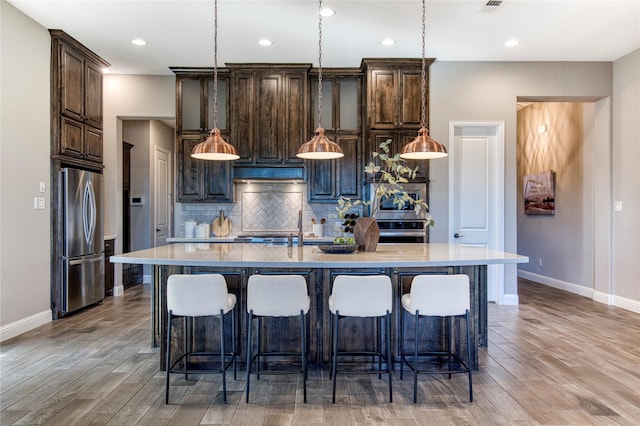 kitchen featuring a sink, wood finished floors, backsplash, and freestanding refrigerator