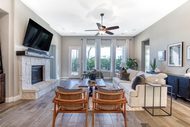 living room with light wood finished floors, baseboards, and a stone fireplace