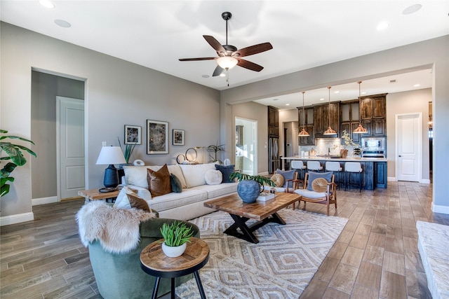 living room featuring wood finish floors, recessed lighting, a ceiling fan, and baseboards