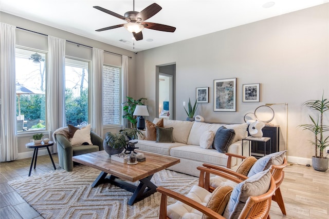 living area with visible vents, light wood-type flooring, a ceiling fan, and baseboards