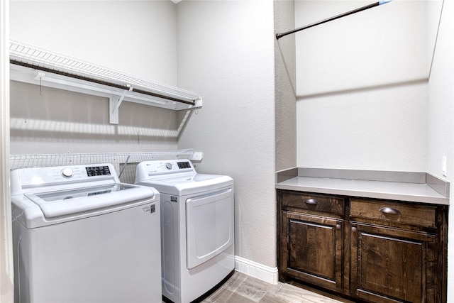 washroom with light wood finished floors, washing machine and clothes dryer, a textured wall, laundry area, and baseboards