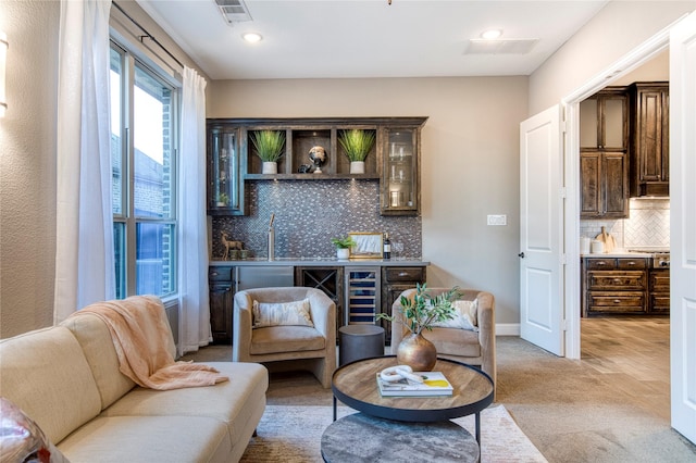 sitting room featuring baseboards, light colored carpet, visible vents, and wet bar