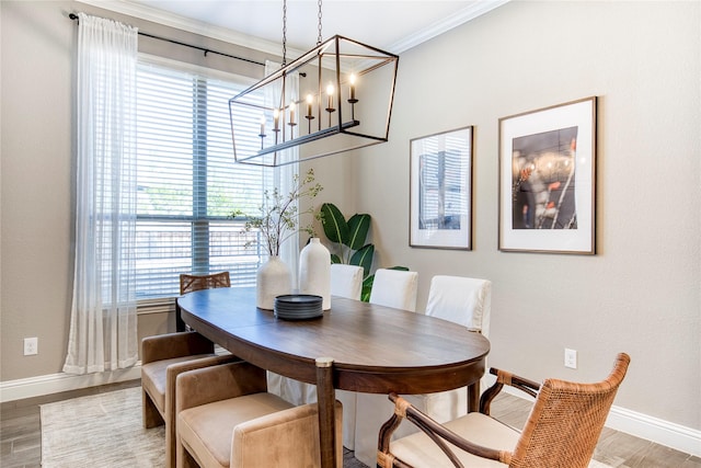 dining room featuring light wood-style floors, crown molding, and baseboards