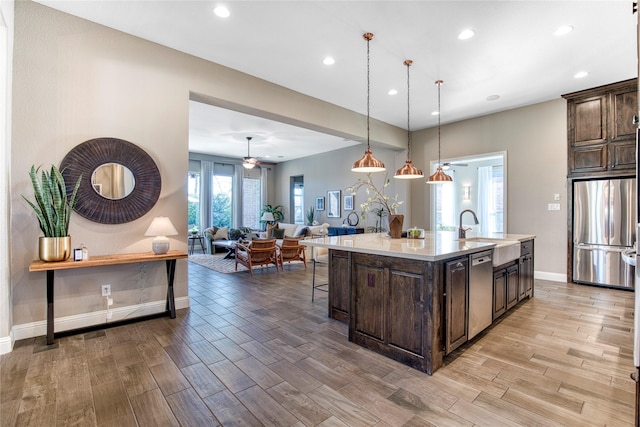 kitchen featuring dark brown cabinetry, stainless steel appliances, a sink, and light countertops