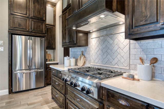 kitchen featuring stainless steel appliances, tasteful backsplash, dark brown cabinets, and custom range hood