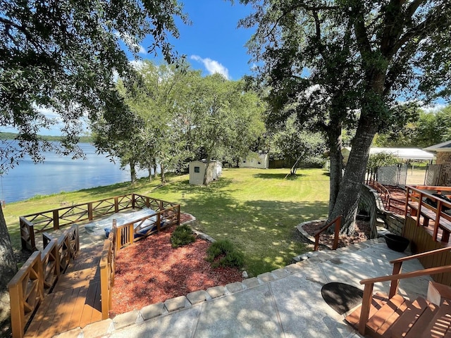 view of yard featuring a water view, an outdoor structure, and a storage shed