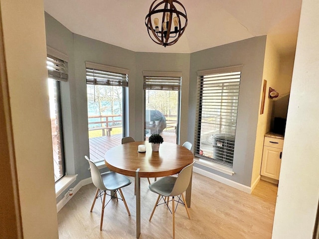 dining area with a chandelier, light wood-type flooring, and baseboards