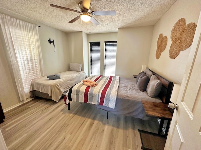 bedroom featuring a ceiling fan, a textured ceiling, and wood finished floors