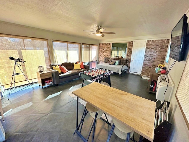 dining space with brick wall, ceiling fan, and a textured ceiling