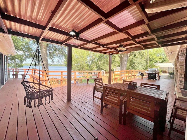 wooden terrace with area for grilling, outdoor dining area, and a water view