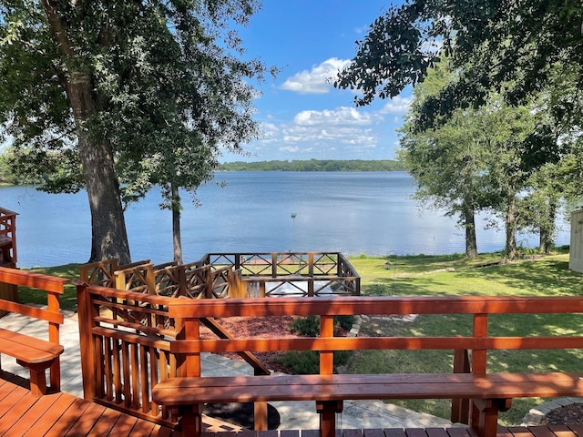 wooden deck featuring a water view and a lawn