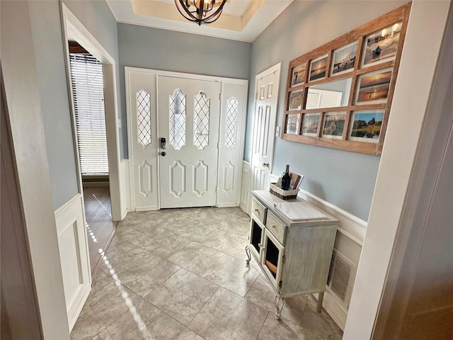 entryway with visible vents, crown molding, and an inviting chandelier