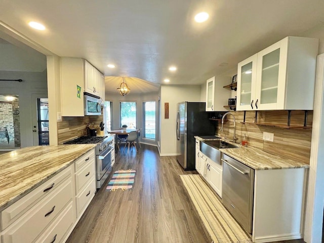 kitchen with stainless steel appliances, a sink, white cabinetry, and decorative backsplash