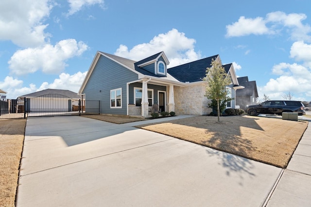 view of front of house with stone siding, driveway, fence, and a gate