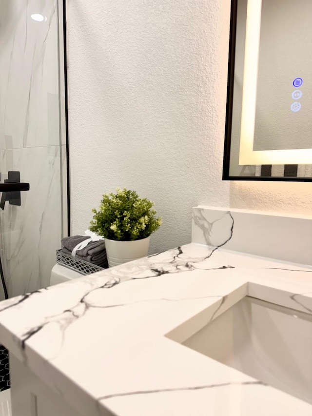 bathroom featuring toilet, a textured wall, and vanity