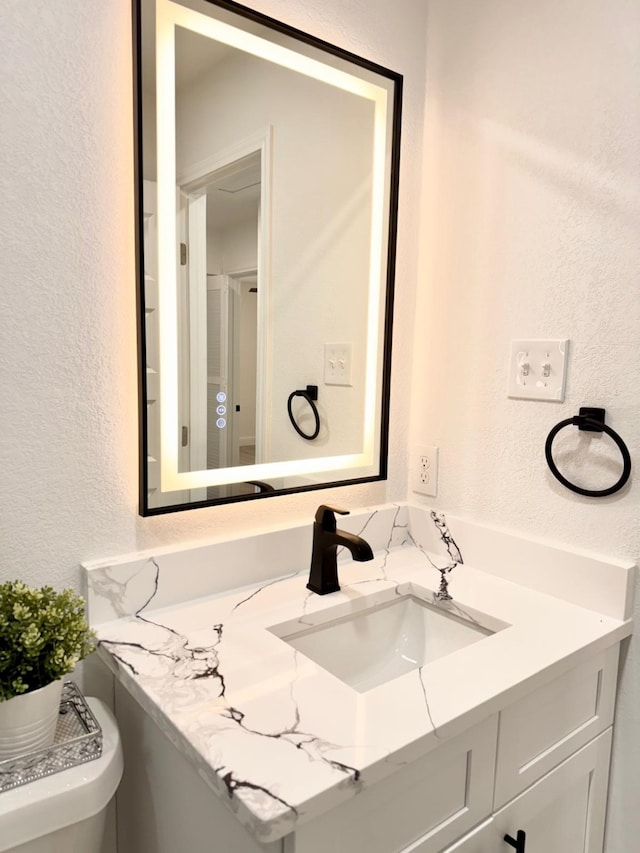 bathroom featuring a textured wall and vanity