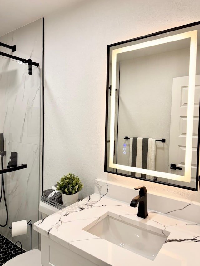 full bath featuring toilet, vanity, and a marble finish shower