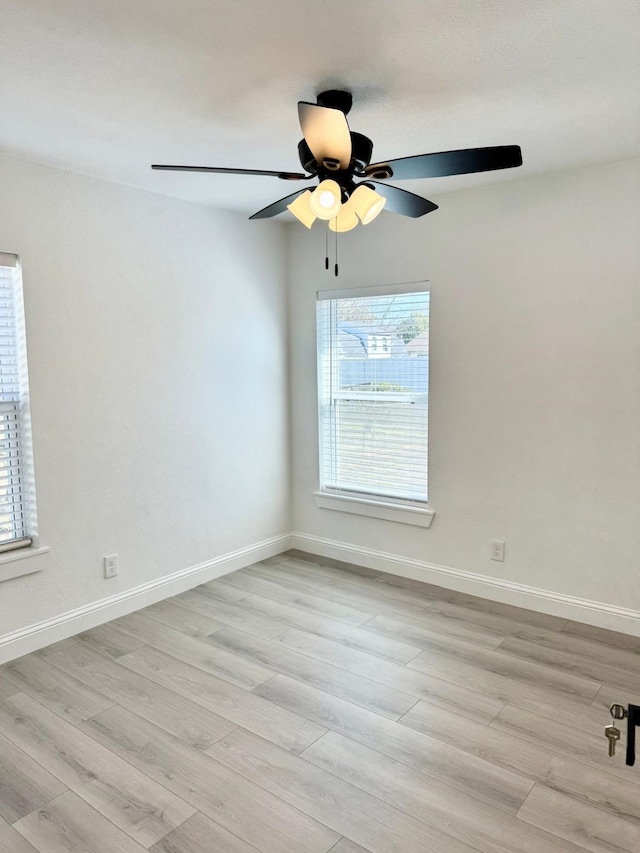 spare room featuring light wood-style flooring, baseboards, and ceiling fan