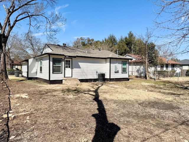 rear view of property featuring entry steps, central air condition unit, and fence