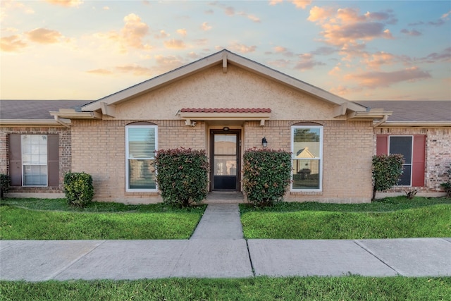 ranch-style home with a front lawn, brick siding, and stucco siding