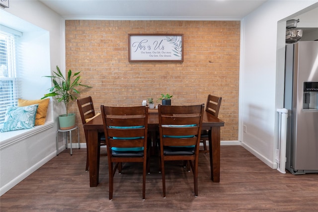 dining room with brick wall, crown molding, baseboards, and wood finished floors