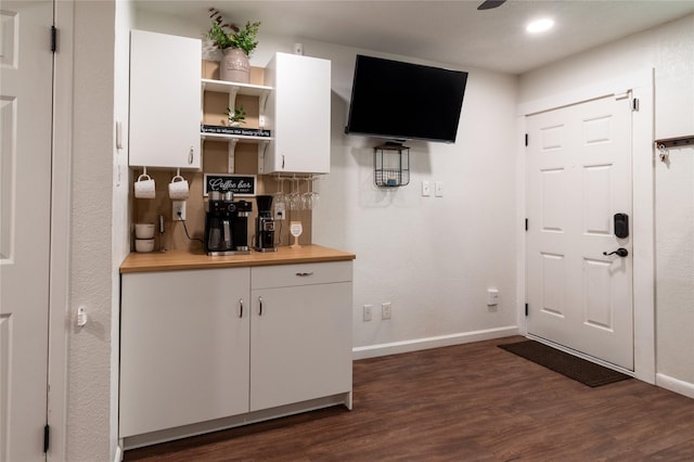 bar featuring a dry bar, a ceiling fan, baseboards, and dark wood-style flooring