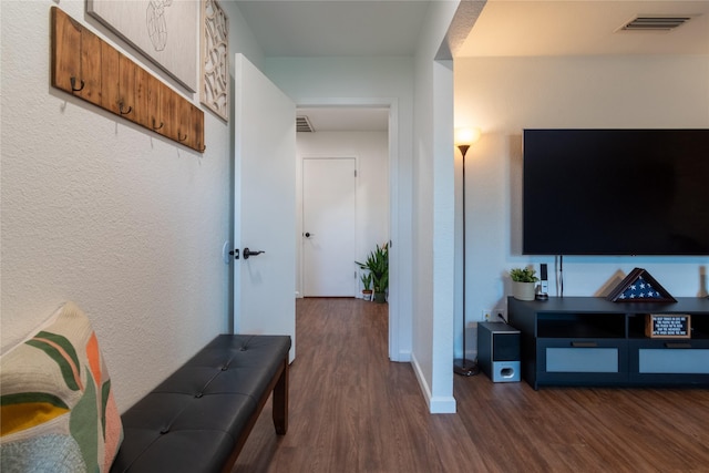 corridor with baseboards, visible vents, wood finished floors, and a textured wall