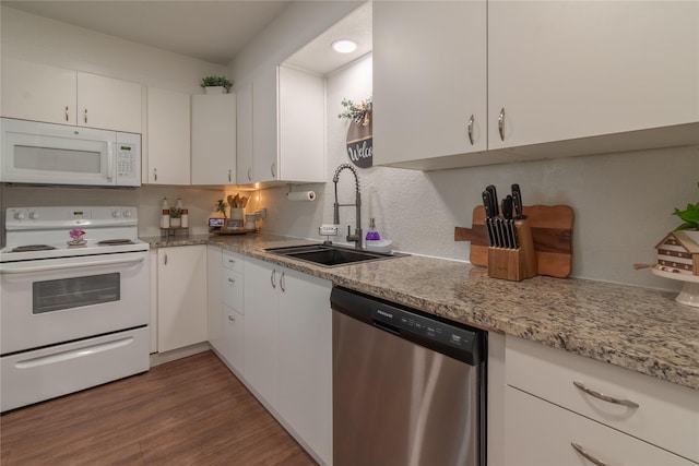 kitchen with tasteful backsplash, white cabinetry, a sink, wood finished floors, and white appliances