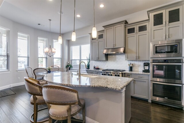 kitchen with visible vents, gray cabinetry, appliances with stainless steel finishes, a sink, and under cabinet range hood