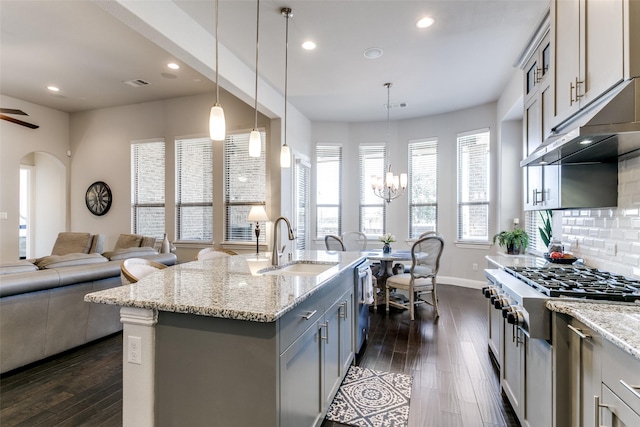 kitchen featuring arched walkways, tasteful backsplash, appliances with stainless steel finishes, open floor plan, and a sink