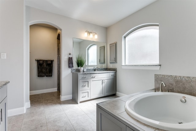 bathroom with baseboards, a garden tub, vanity, and tile patterned floors