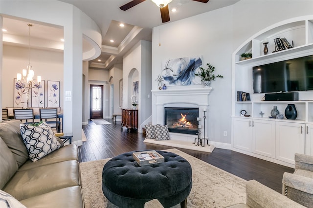 living area featuring recessed lighting, dark wood finished floors, baseboards, built in features, and a glass covered fireplace