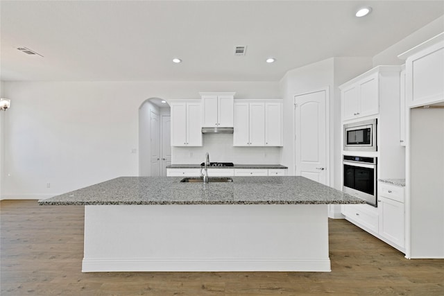 kitchen featuring arched walkways, appliances with stainless steel finishes, a sink, and visible vents